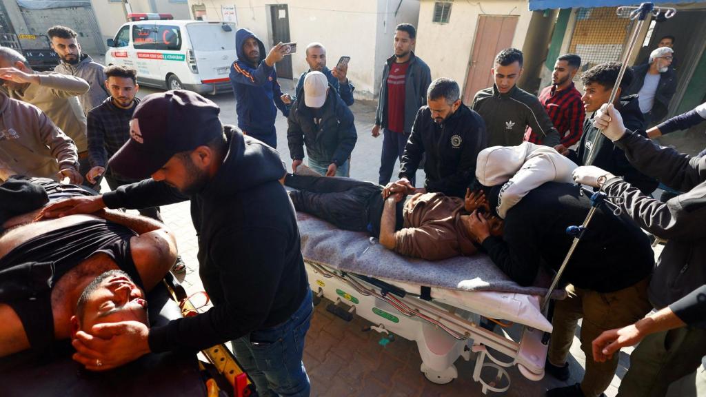 People react as Palestinians carry wounded people following an Israeli attack in front of a school housing displaced people, according to medical staff, at Al-Aqsa Martyrs Hospital in Deir al-Balah, central Gaza Strip, on April 6, 2026