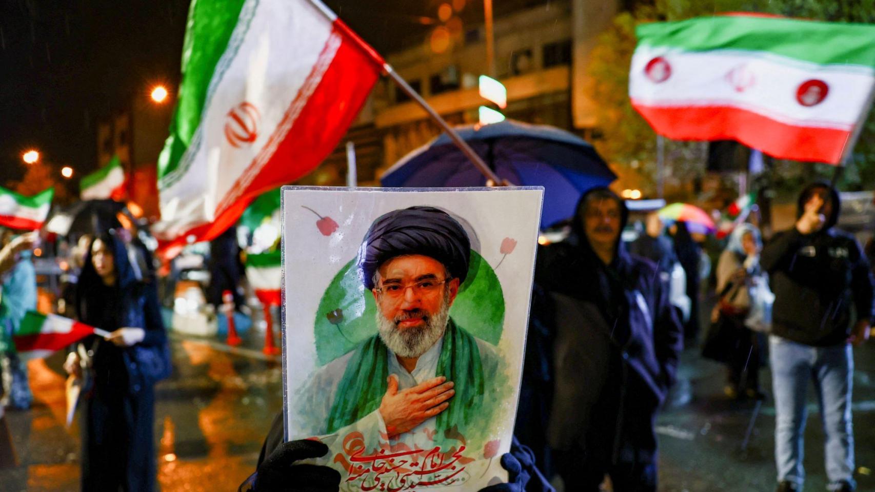 Manifestantes muestran un cartel con la imagen de Mojtaba Jamenei en una calle de Teherán.