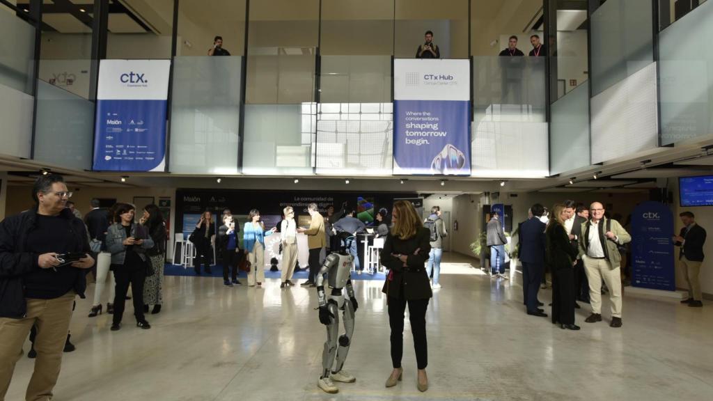 Marta Raspall, codirectora de CTx Tech Experience interacciona con uno de los robots exhibidos durante el evento tecnológico.