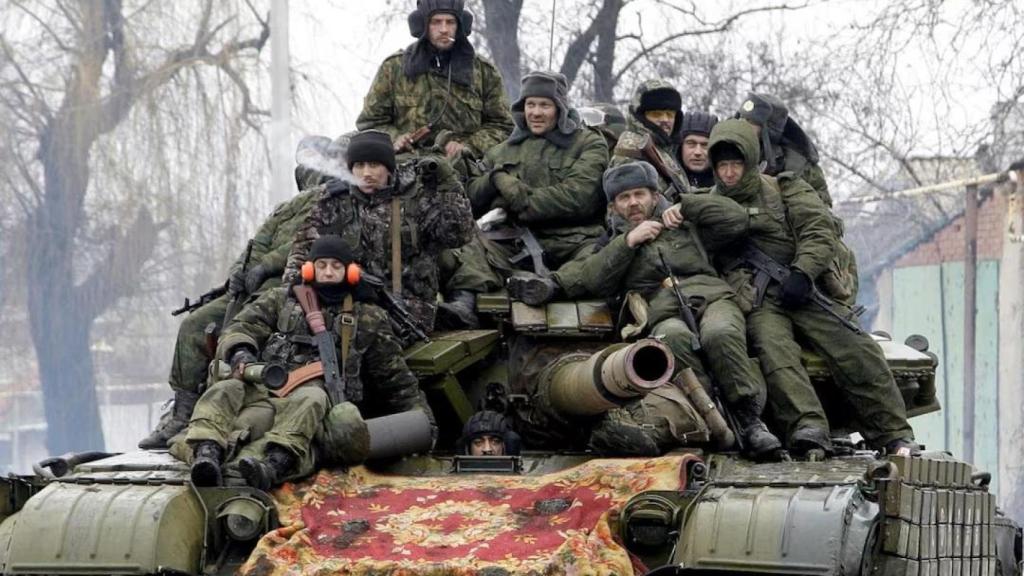 Russian soldiers boarding a combat tank.