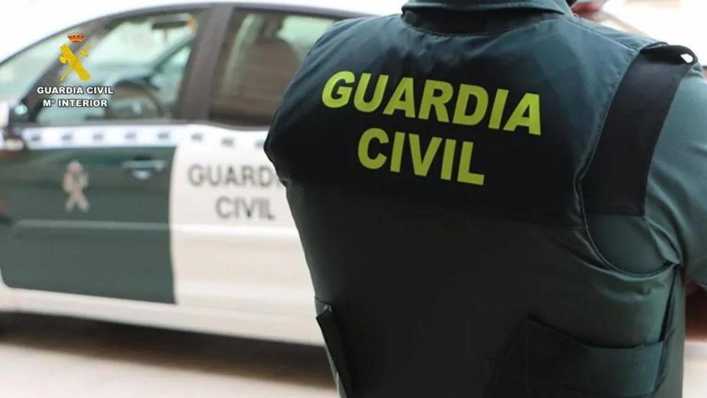 Un agente de la Guardia Civil junto a un vehículo oficial.