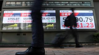 Los transeúntes pasan junto a pantallas que muestran el índice Nikkei de la bolsa japonesa.