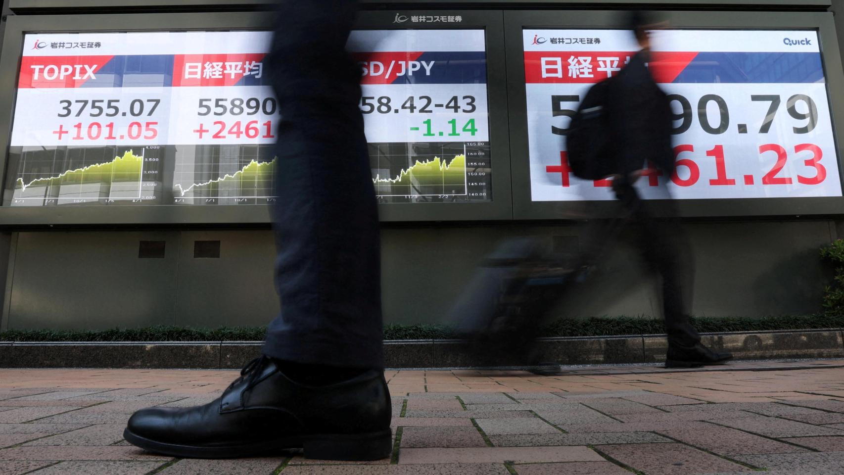 Los transeúntes pasan junto a pantallas que muestran el índice Nikkei de la bolsa japonesa.