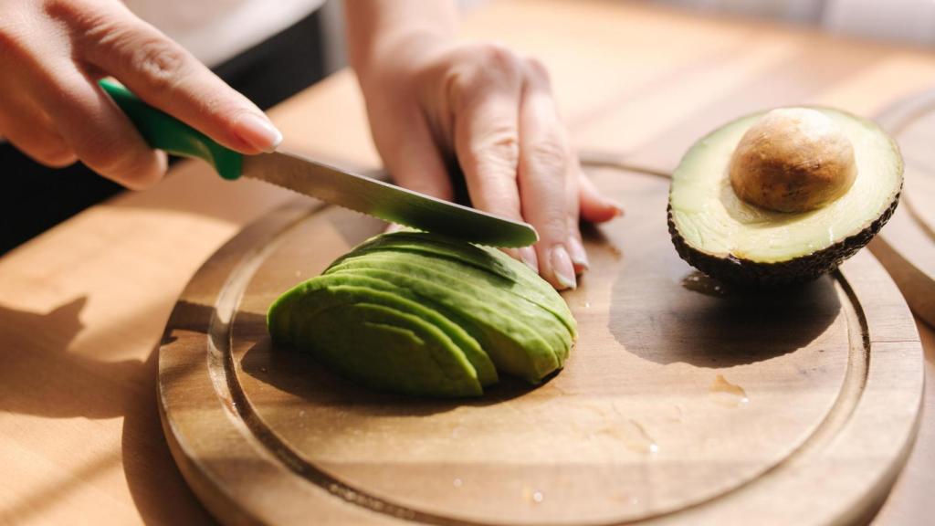 Una persona cortando un aguacate.