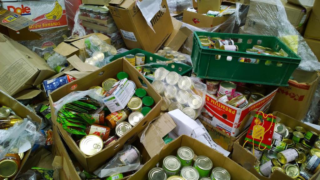 ECajas de cartón con alimentos enlatados en latas en suelo.