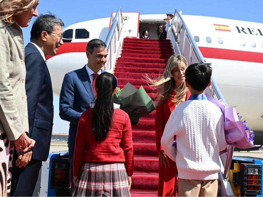 Unos niños entregan un ramo de flores a Pedro Sánchez y Begoña Gómez, este sábado a su llegada a Pekín..