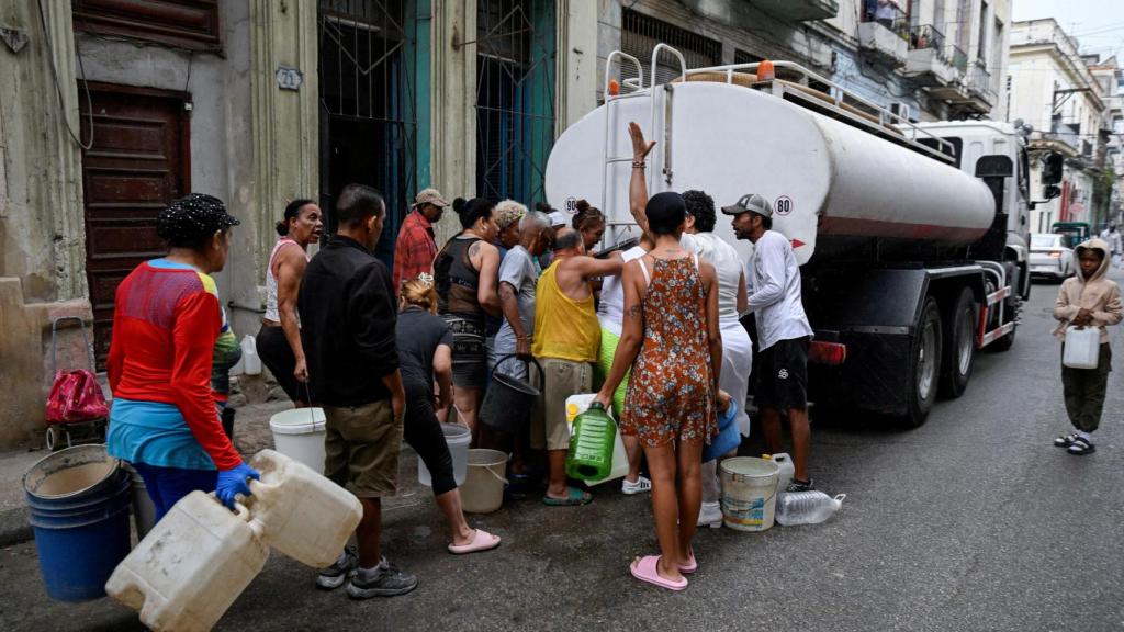 Several people gather around a tanker truck to fill buckets and other containers, as severe fuel shortages have disrupted the pumping and distribution of water, in Havana, Cuba, on March 19, 2026.