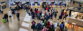 Vista de la terminal de Alvedro con pasajeros en colas de facturación.