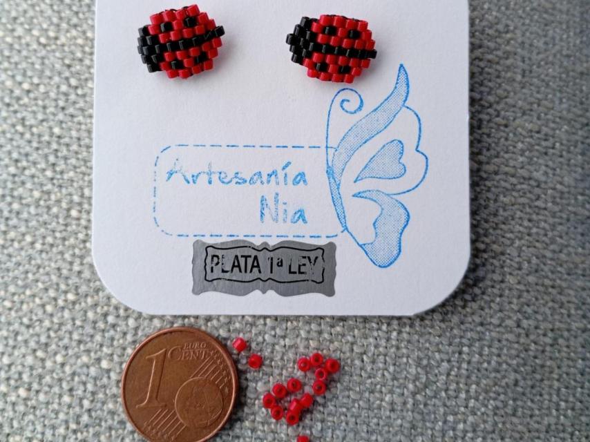 Diseño de mariquitas con delicas, situadas al lado de un céntimo para ver su tamaño.