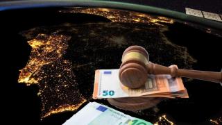 Fotomontaje de la Península Ibérica durante la noche y un mazo judicial con dinero.