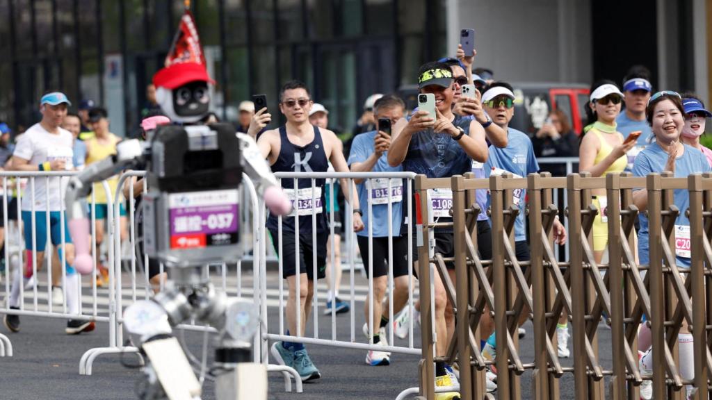 Varios deportistas filman a uno de los robots participantes.