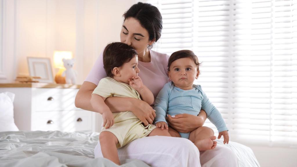 Una madre con dos bebés en brazos.