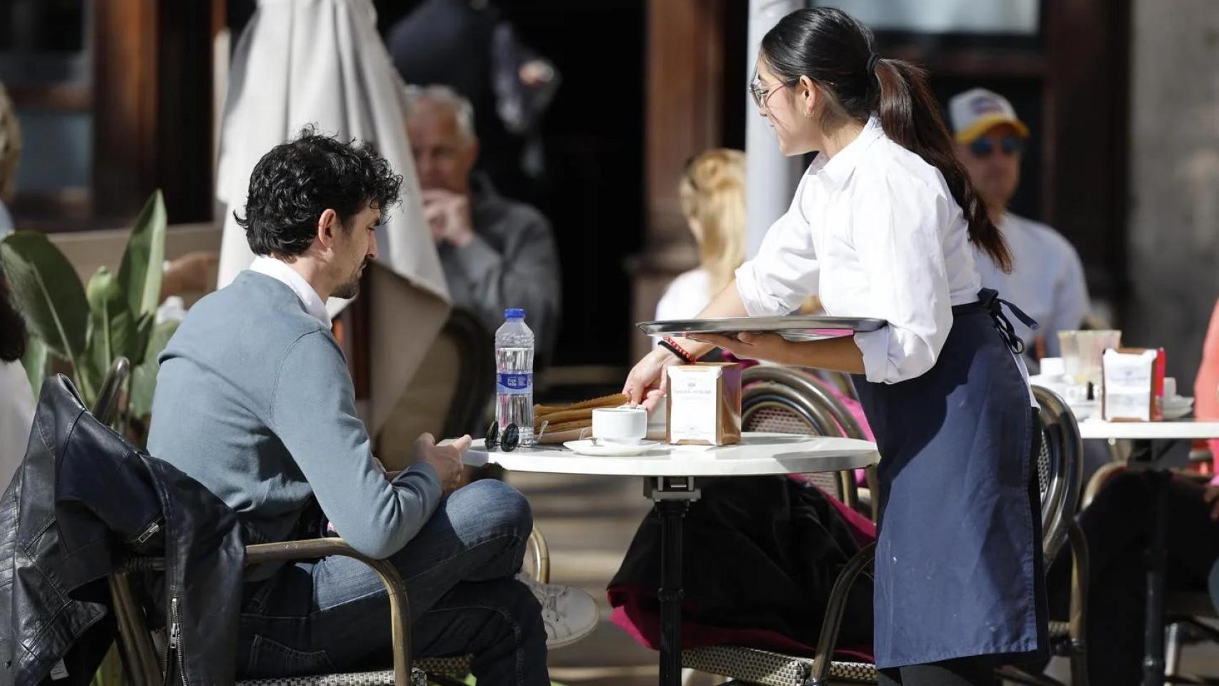 Una camarera atiende una mesa en una terraza.