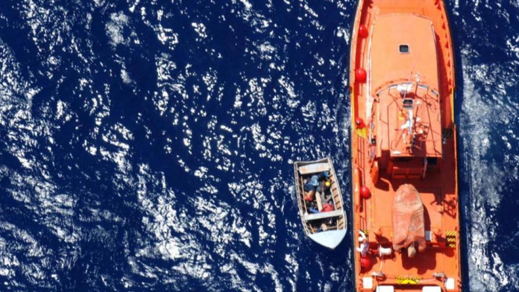 Vista aérea de una embarcación de Salvamento Marítimo rescatando a una patera en alta mar.