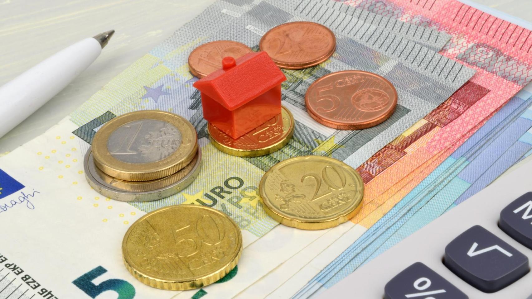 Una casa de juguete y dinero en metálico