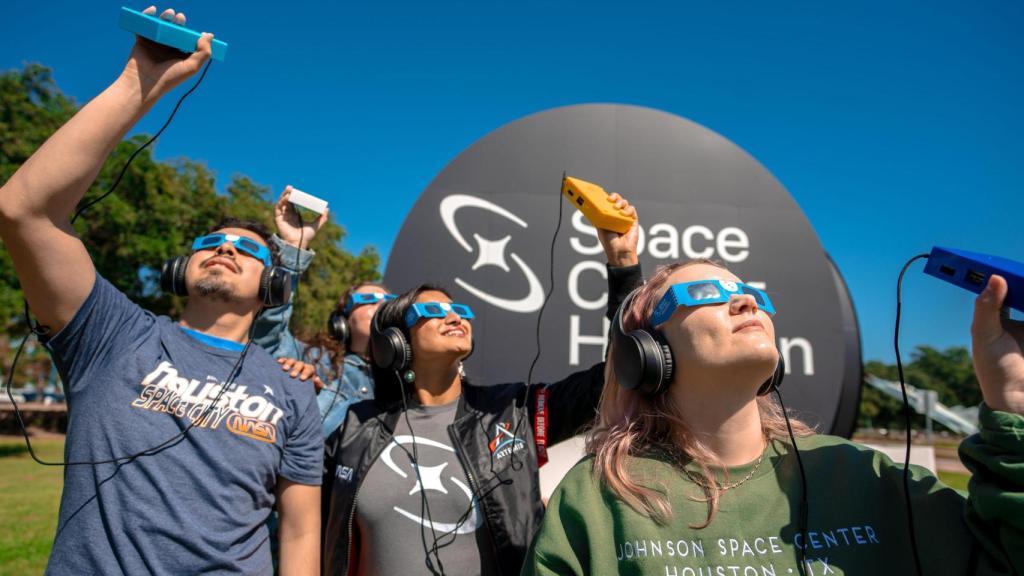 Un grupo de personas con discapacidad visual utilizando dispositivos para oír el eclipse anular de 2023 desde Houston