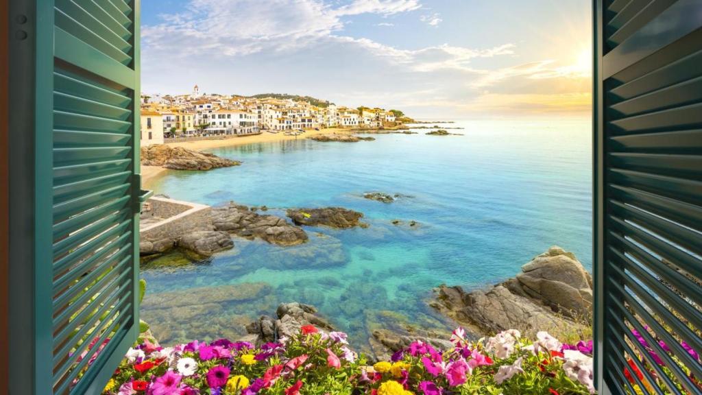 Vista a través de una ventana abierta de la ciudad de Calella de Palafrugell, España, en la Costa Brava mientras se pone el sol