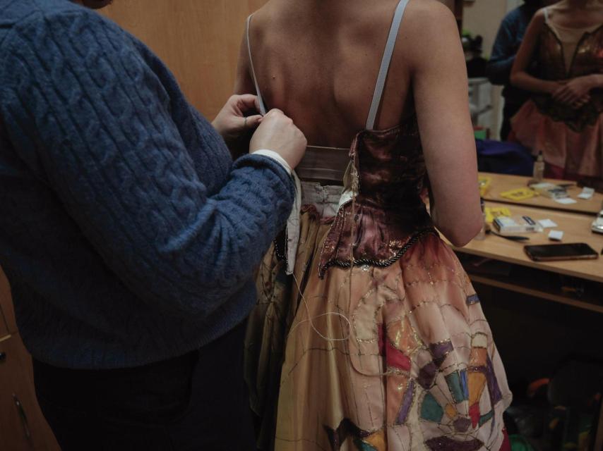 Una de las encargadas de vestuario del Teatro de la Ópera y el Ballet de Járkiv ajusta el corsé de una de las bailarinas en los camerinos.