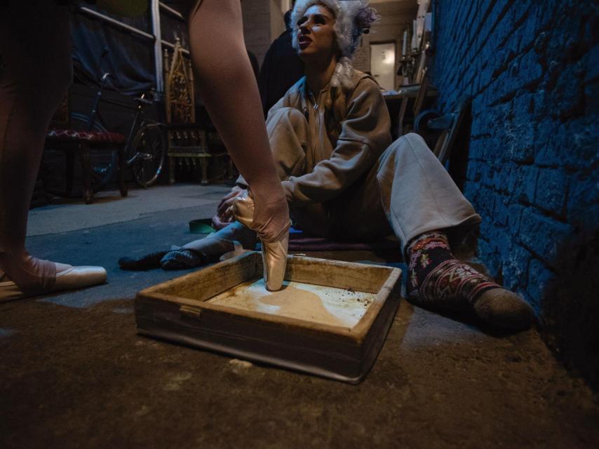 Dos bailarinas del ballet de Járkiv conversan detrás del  escenario temporal construido en el sótano del teatro.
