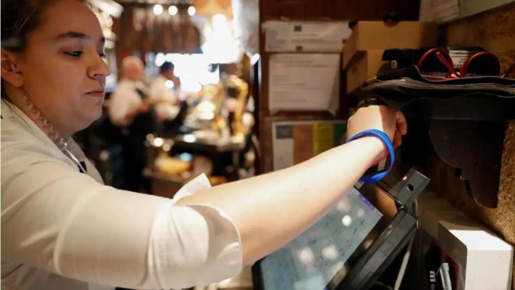 Una trabajadora cobra dentro de un bar.