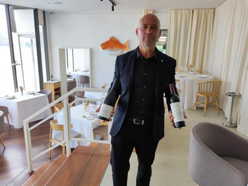Ramiro Fernández en Tira do Playa con una botella de vino O Soro y otra de Vega Sicilia.