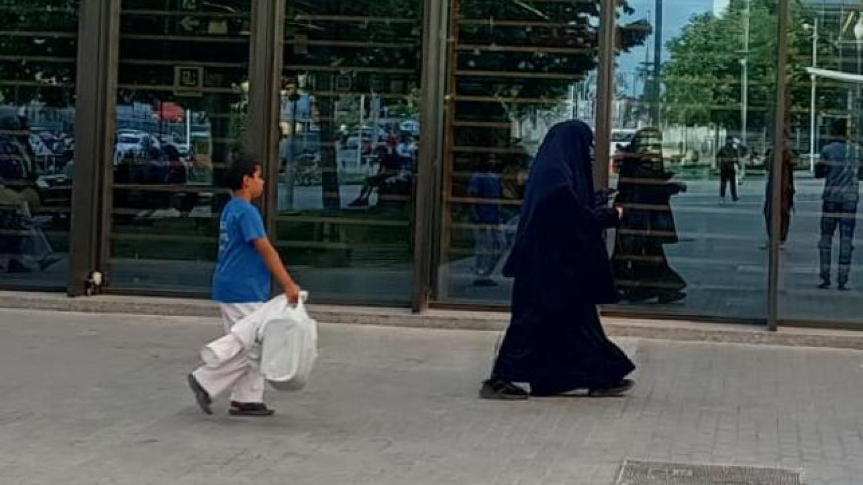 Una mujer con burka pasea con su hijo por los alrededores de la estación de trenes de Lérida.