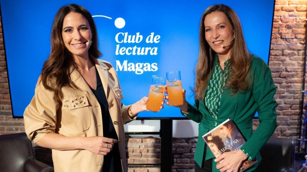 Moderadora e invitada brindan tras terminar la conversación.
