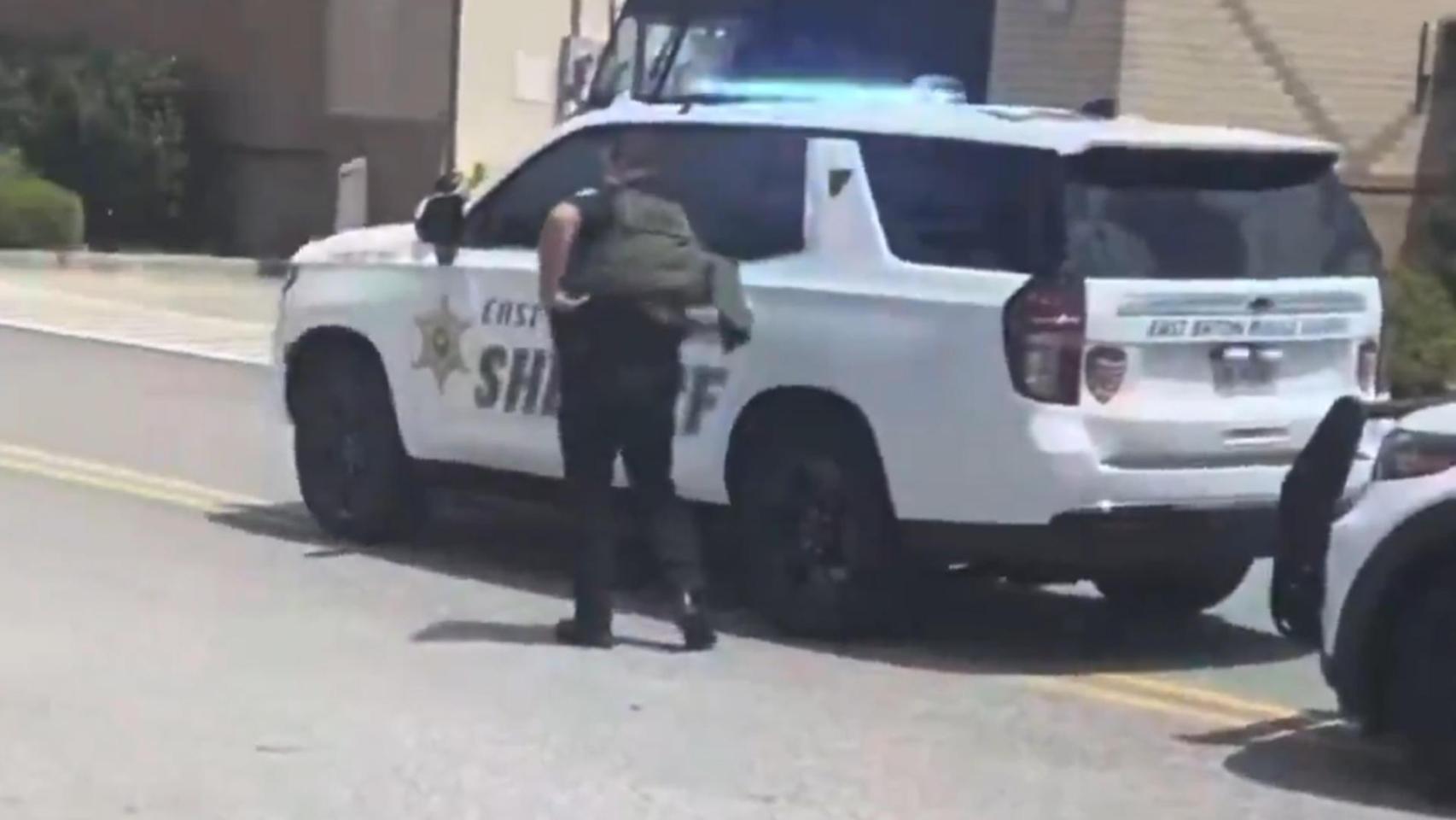 Un oficial de policía se resguarda tras un vehículo durante el tiroteo en Baton Rouge.