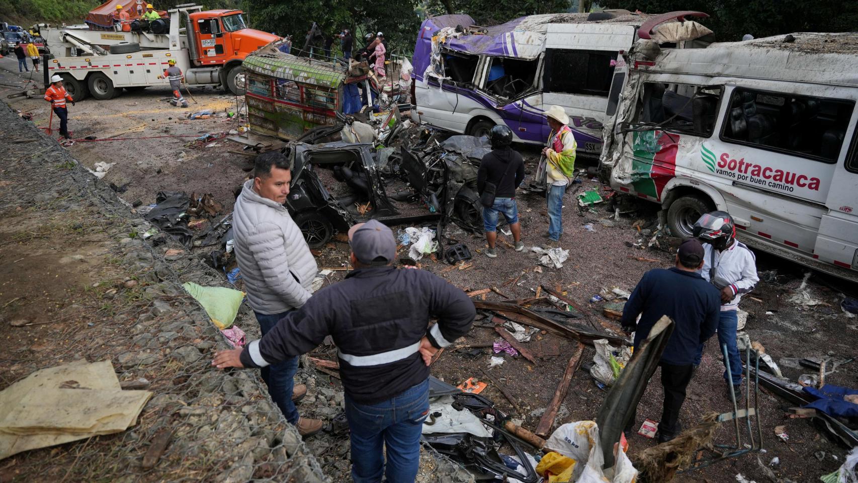 Varias personas permanecen junto a vehículos destruidos tras un atentado con explosivos que dejó más de una docena de muertos en la Carretera Panamericana, en la zona de El Túnel, Cajibio, Colombia.