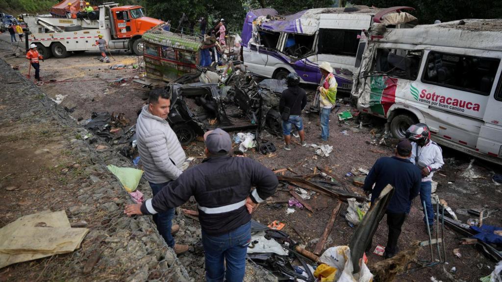 Varias personas permanecen junto a vehículos destruidos tras un atentado con explosivos que dejó más de una docena de muertos en la Carretera Panamericana, en la zona de El Túnel, Cajibio, Colombia.