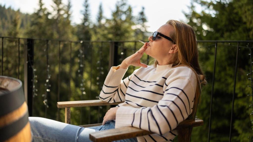 Imagen de ilustración de una mujer fumando en una terraza.