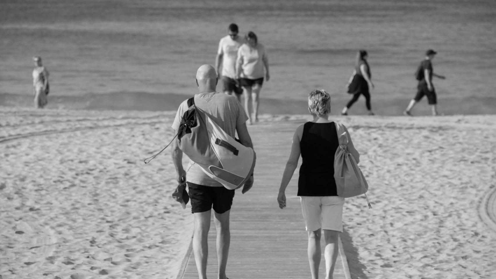 Una pareja camina hacia la playa en un típico día veraniego en España.