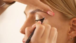 Maquilladora haciendo eyeliner a la clienta.