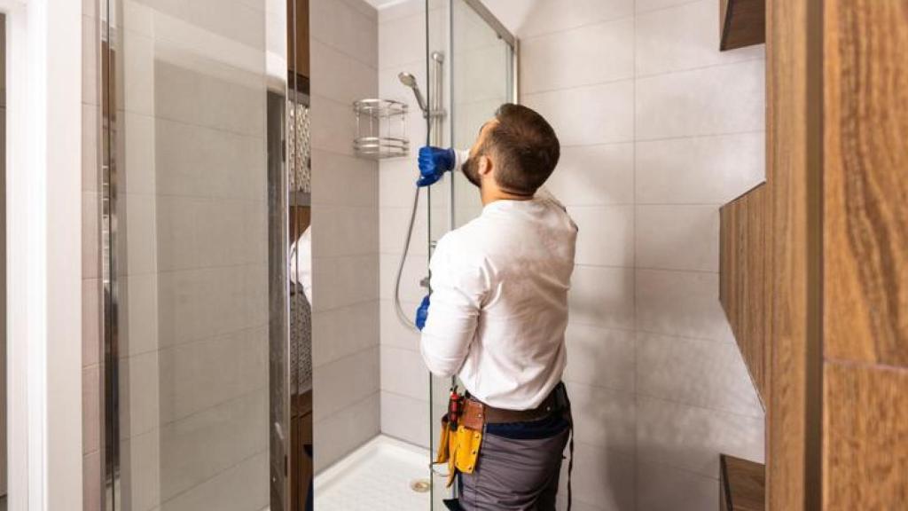Un fontanero cambiando una bañera por una ducha.
