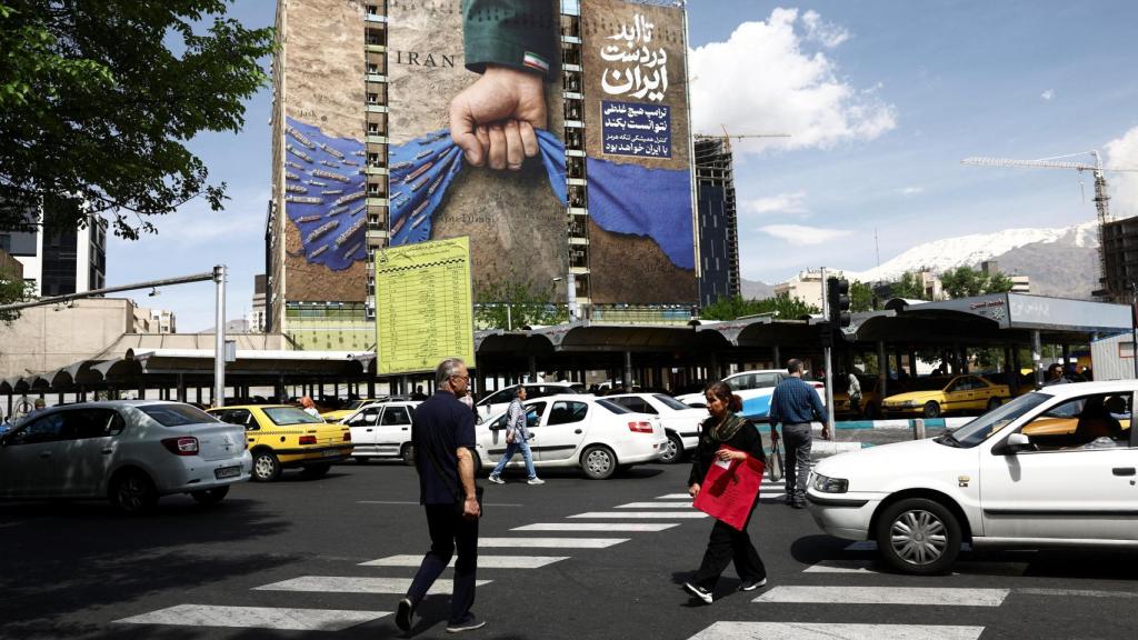 Ciudadanos de Teherán pasan frente a una pancarta que representa el control iraní del estrecho de Ormuz.