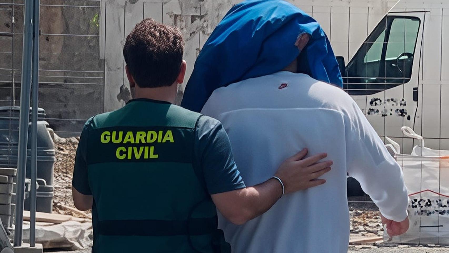 Un agente de la Guardia Civil traslada a uno de los detenidos 