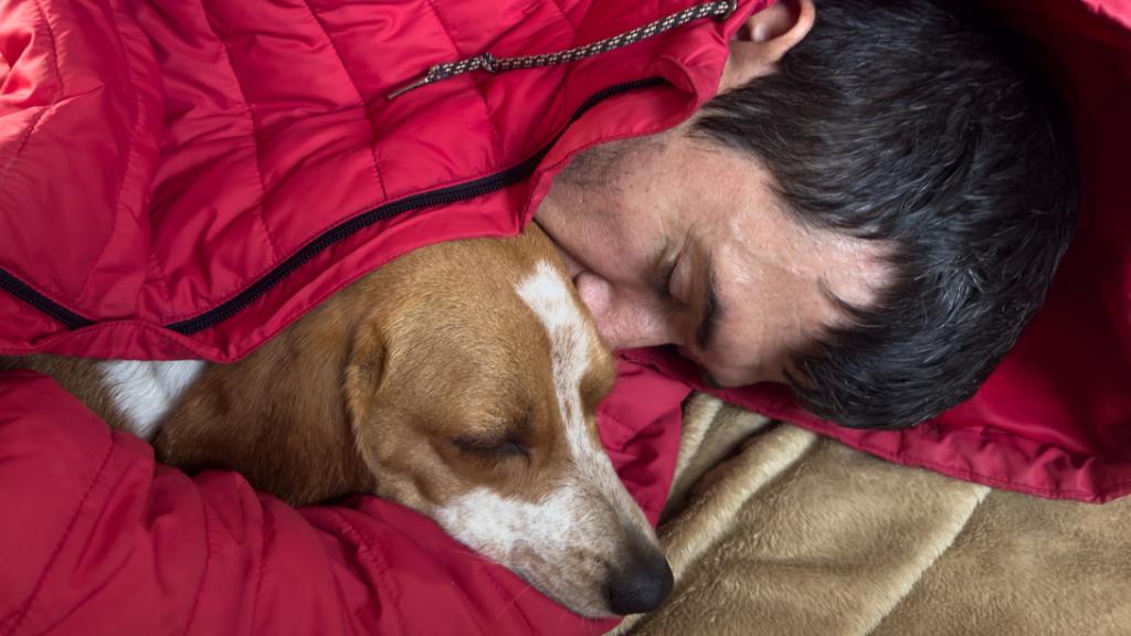 Un hombre durmiendo con un perro.