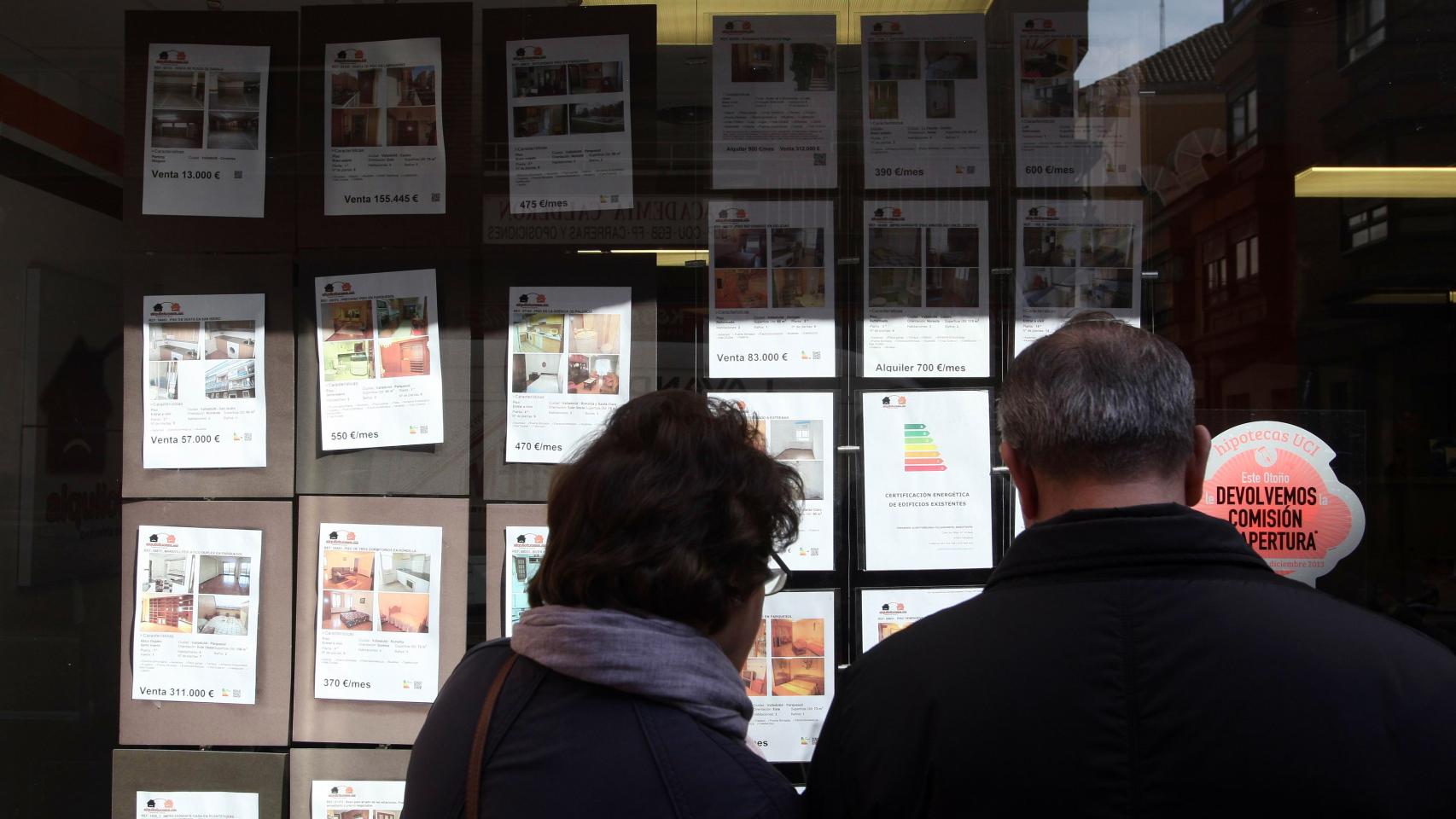 Una pareja mira los anuncios de una inmobiliaria en Valladolid