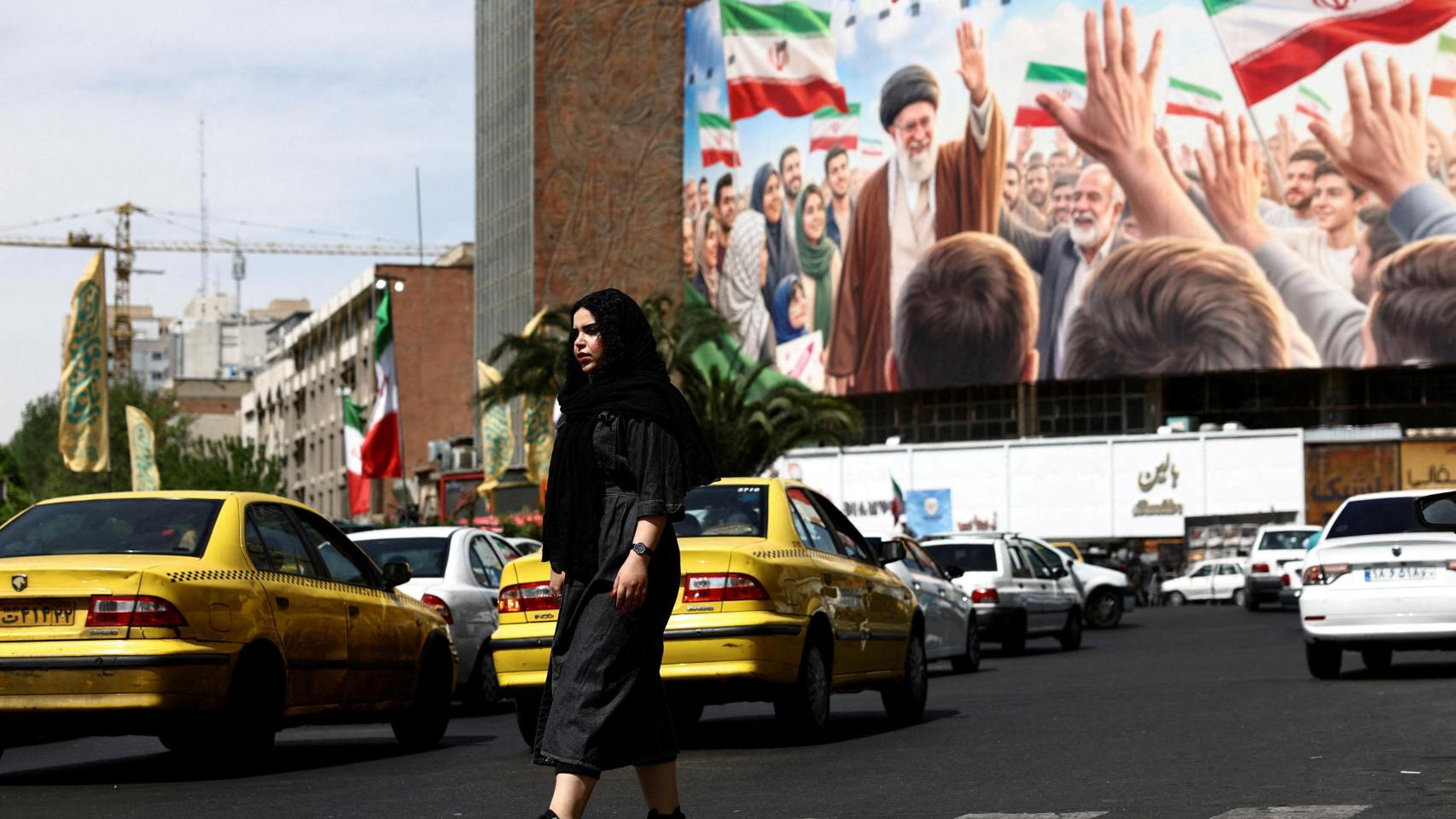 Una mujer pasa junto a una valla publicitaria con la imagen del difunto líder supremo de Irán, el ayatolá Ali Jamenei, en un edificio de Teherán.
