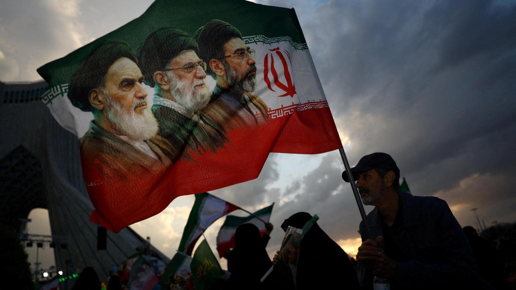 Un hombre sostiene una bandera con la imagen del difunto líder de la Revolución Islámica, el ayatolá Ruhollah Khomeini.