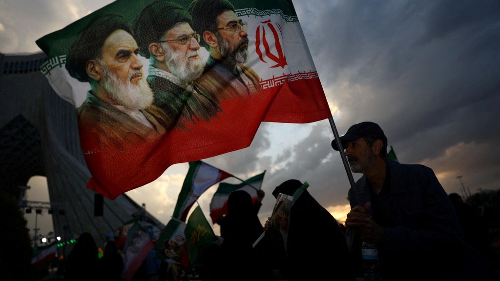 Un hombre sostiene una bandera con la imagen del difunto líder de la Revolución Islámica, el ayatolá Ruhollah Khomeini.