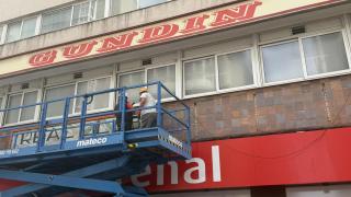 Operarios trabajando en la retirada del cartel exterior.
