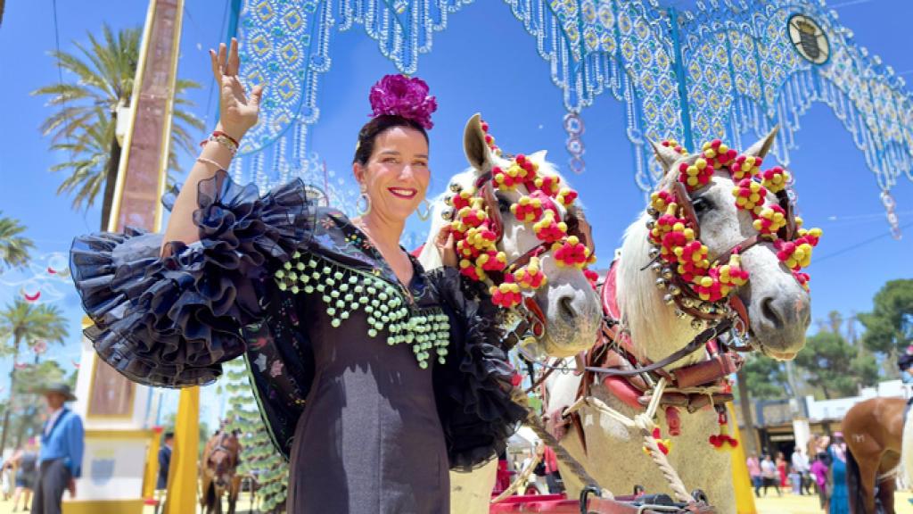 Mujer con el traje típico andaluz junto a caballos en el ferial.