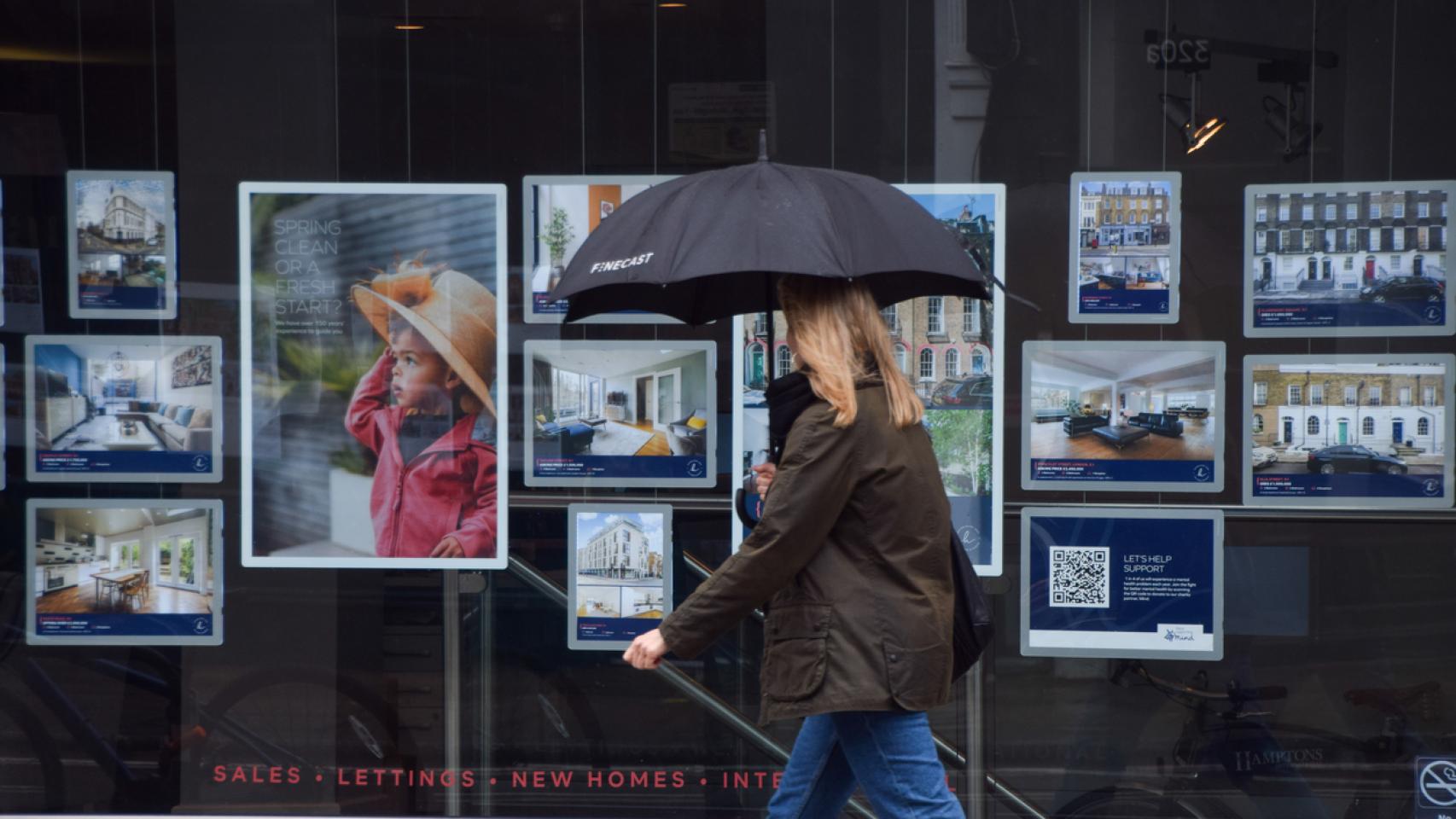 Una mujer delante de una agencia inmobiliaria en Londres