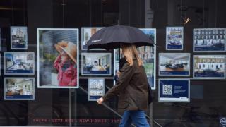 Una mujer delante de una agencia inmobiliaria en Londres