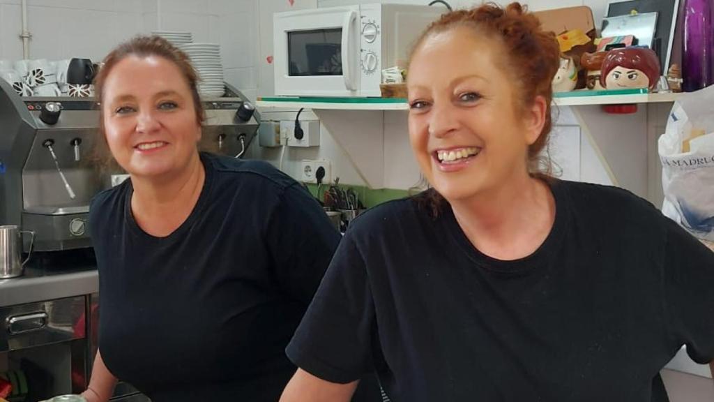 Elisa, sonriente, en primer plano, detrás de la barra de la cantina del IES Beniaján, junto a su empleada y amiga María José. 