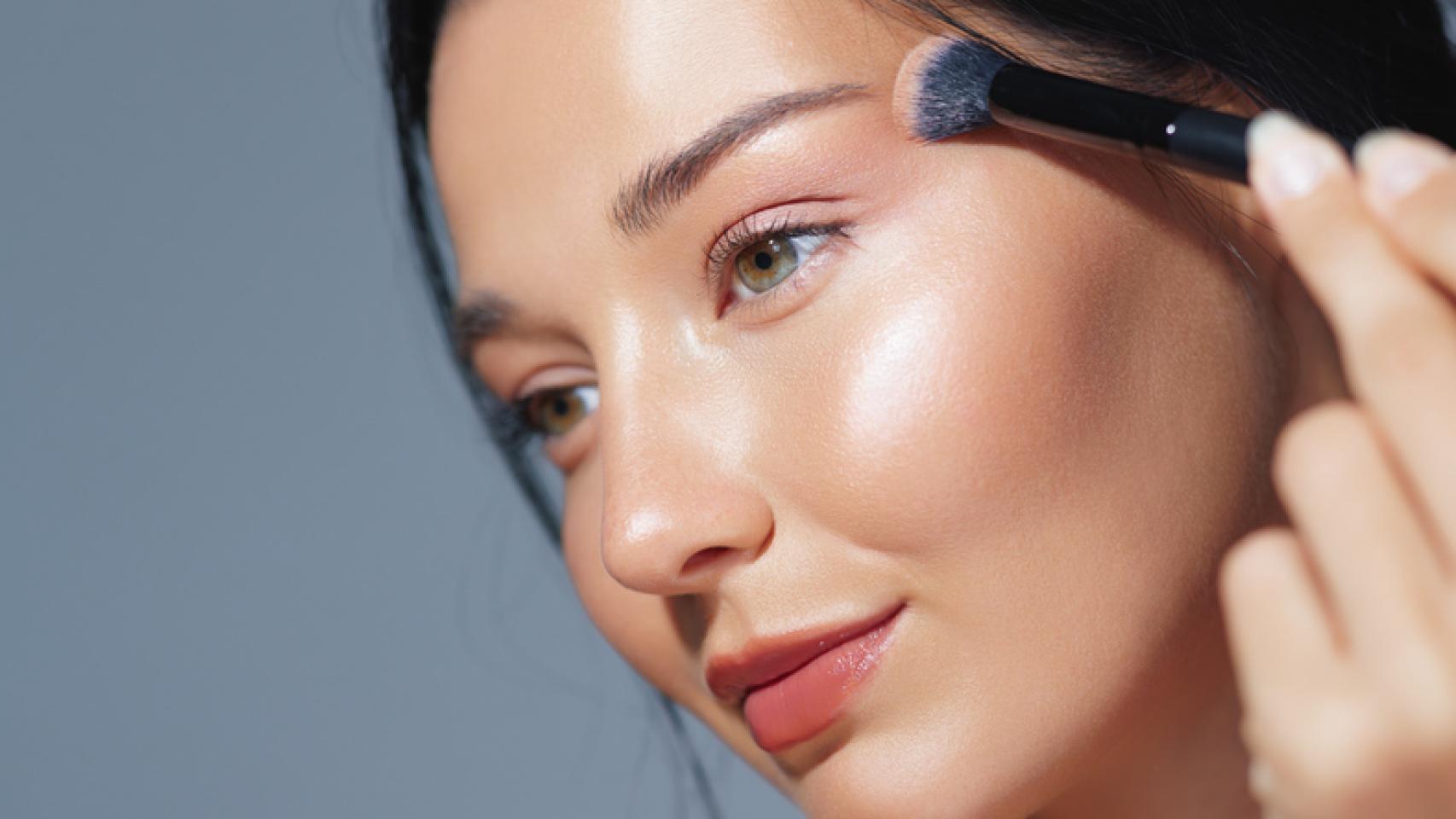 Mujer con brocha de maquillaje.