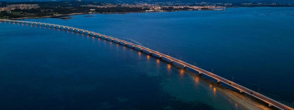 Puente iluminado de la Illa de Arousa al anochecer.
