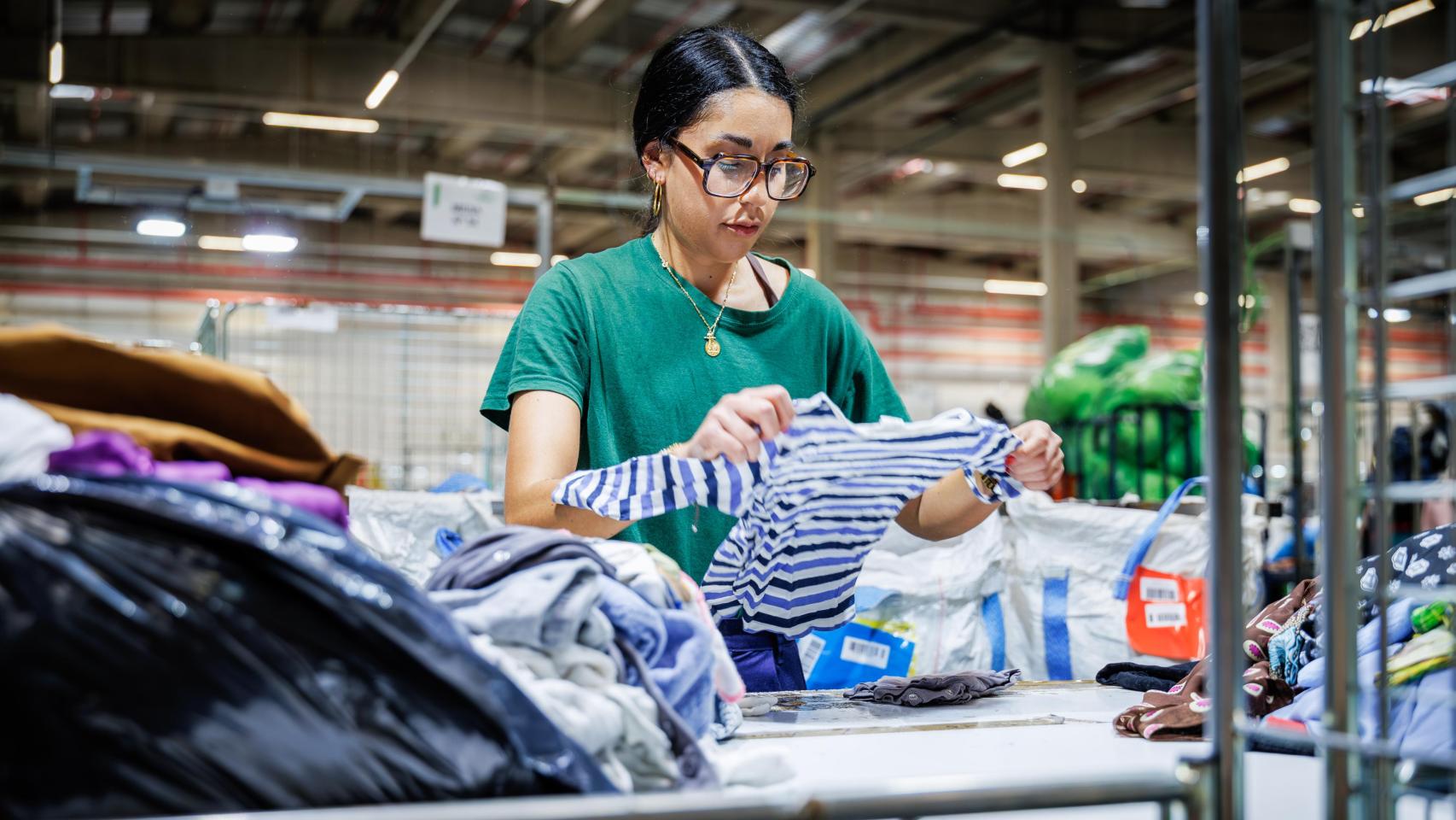 Una empleada de Humana clasifica ropa que ha llegado a la planta.