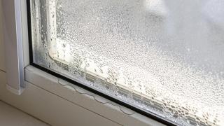 Gotas de condensación acumuladas en una ventana por problemas de humedad en el hogar.